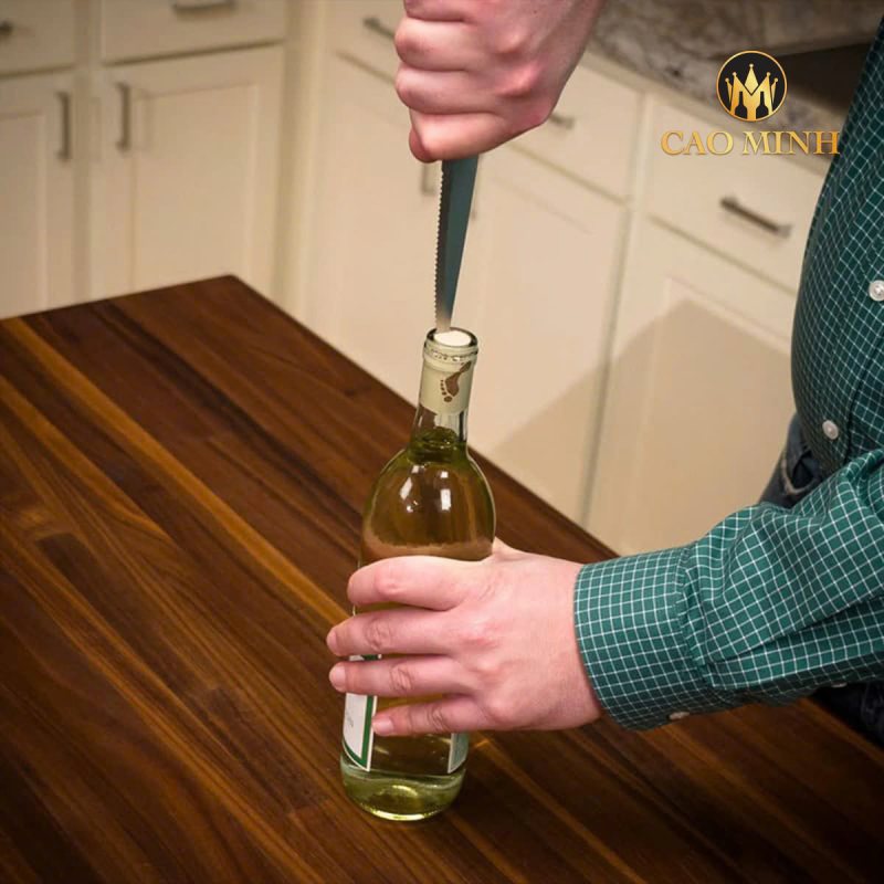 Cắm lưỡi dao vào khe giữa nút bần và thành chai, xoay và kéo nhẹ để nút bần lên