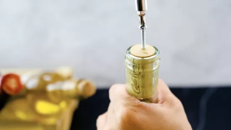 Vặn vít vào nút bần, sau đó dùng búa kẹp vào đầu vít và kéo ra