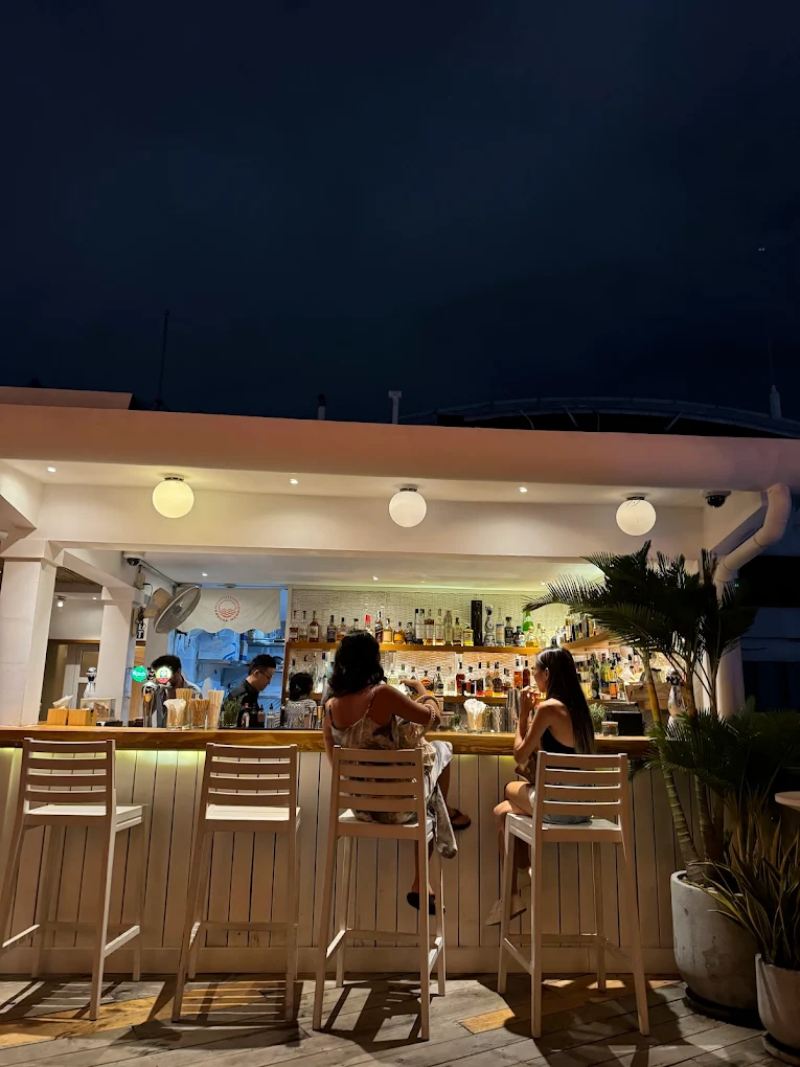 Banana mama rooftop được thiết kế tinh tế với sàn gỗ ấm áp, hệ thống đèn vàng tạo cảm giác thân thiện, cùng những chậu cây xanh mướt và ghế sofa với cushion rực rỡ sắc màu.